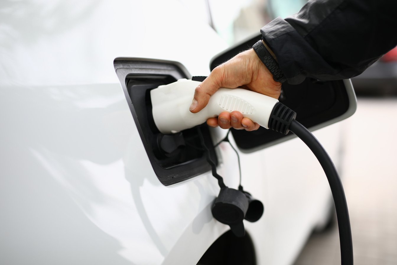 White Electric Car Be Recharged at Charging Station.